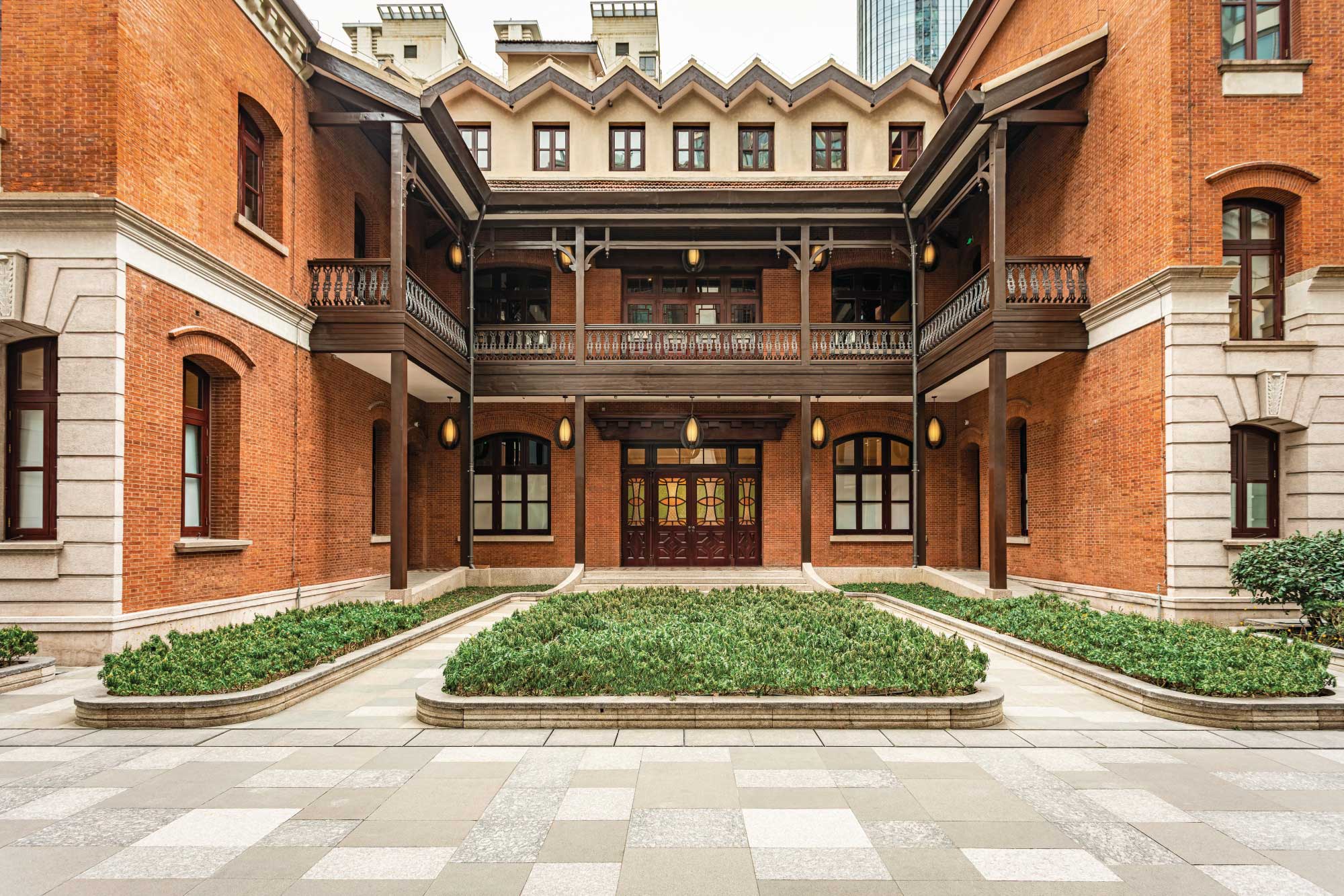 Historic brick façade of Cha House in Shanghai, home to Harrods Residence, showcasing restored architectural details and landscaped courtyard.