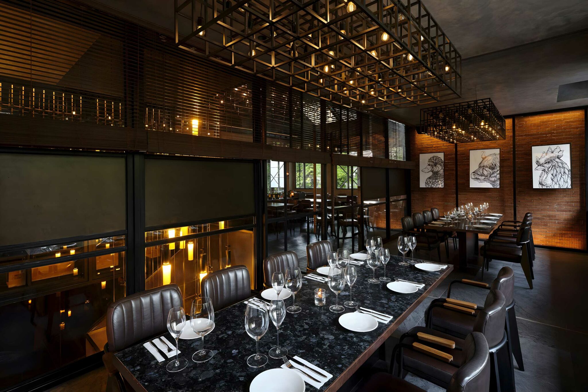 Private dining room at Meatsmith Jakarta, featuring charcoal-toned finishes, custom pendant lighting, leather seating, and contemporary animal sketch artworks for a refined, masculine ambience.