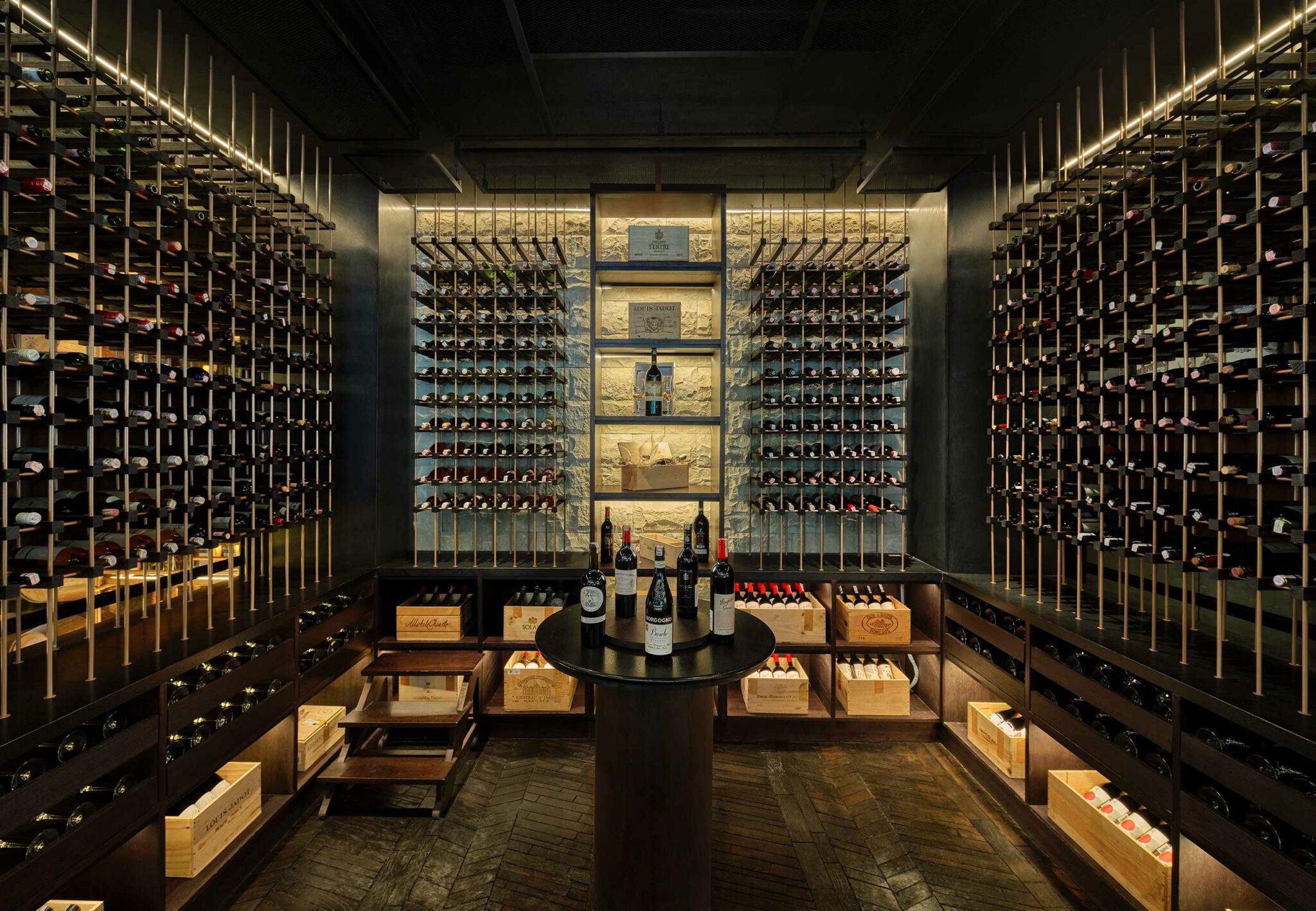 Dedicated wine room at Meatsmith Jakarta, showcasing floor-to-ceiling bottle displays, backlit stone accents, and a central tasting table that elevates the guest discovery experience.