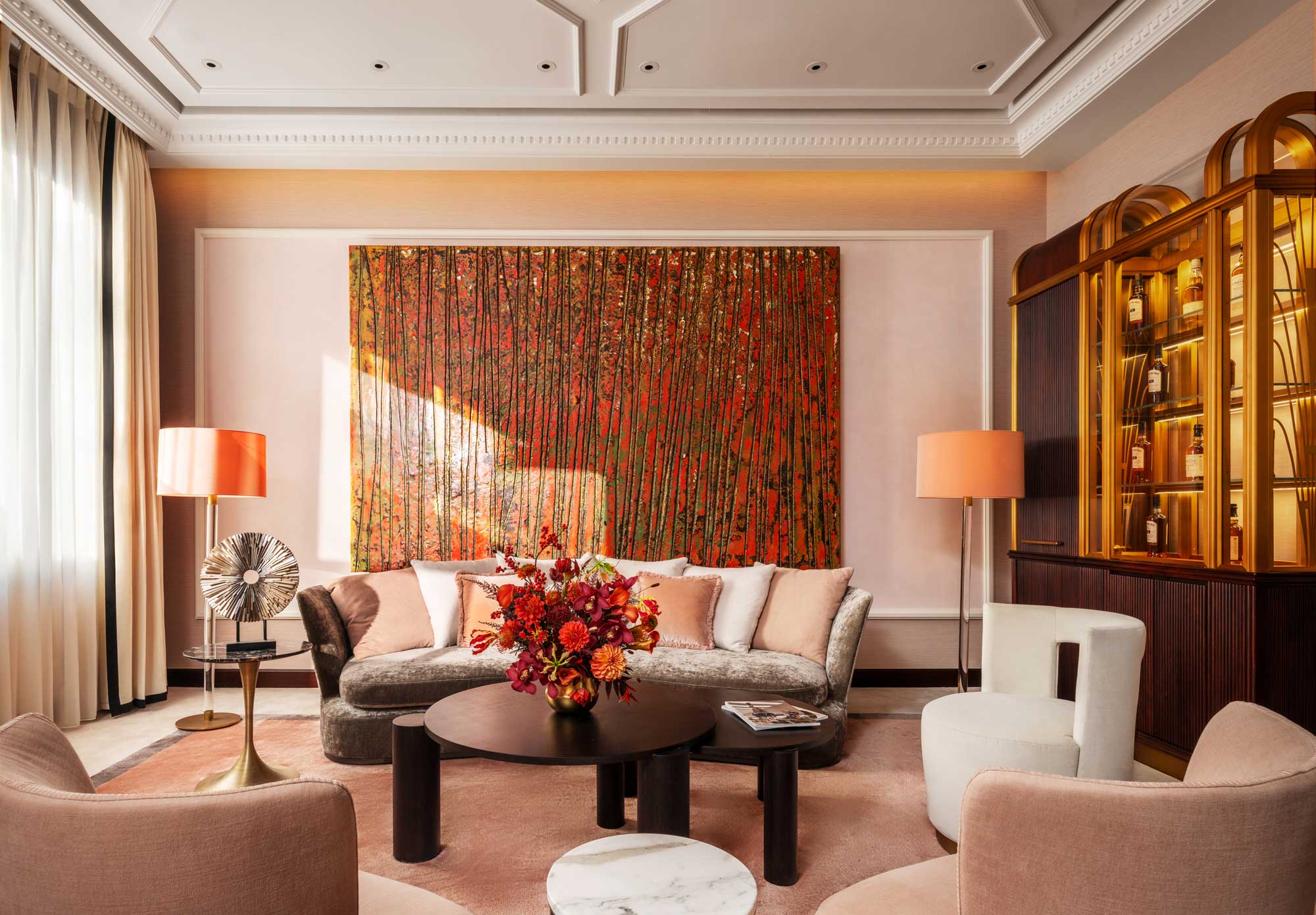 Harrods Residence at Cha House Shanghai — elegant living room with plush seating, warm peach tones, contemporary floral arrangement and a large red-and-gold abstract artwork.