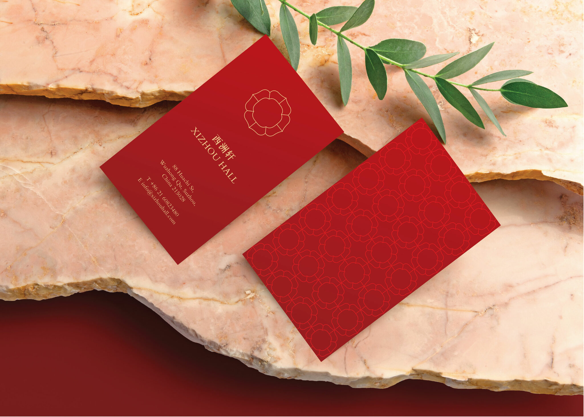 Red Xizhou Hall business cards with gold floral emblem displayed on pink marble with a green branch, showcasing elegant branded stationery design part of the branding