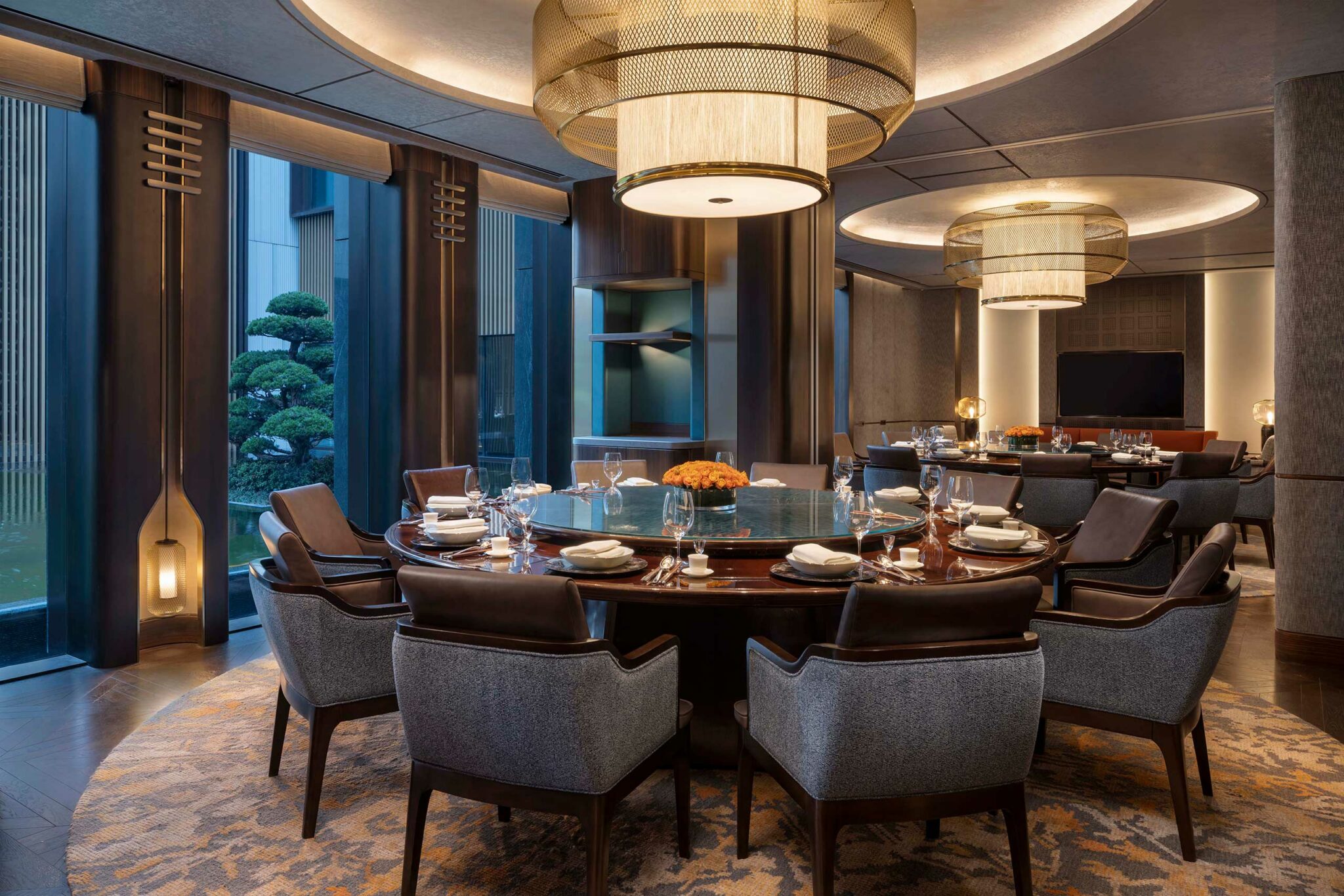 Park Hyatt Suzhou Xizhou Hall private dining room featuring a large round table, modern Chinese décor, warm lighting, and views of the landscaped courtyard.