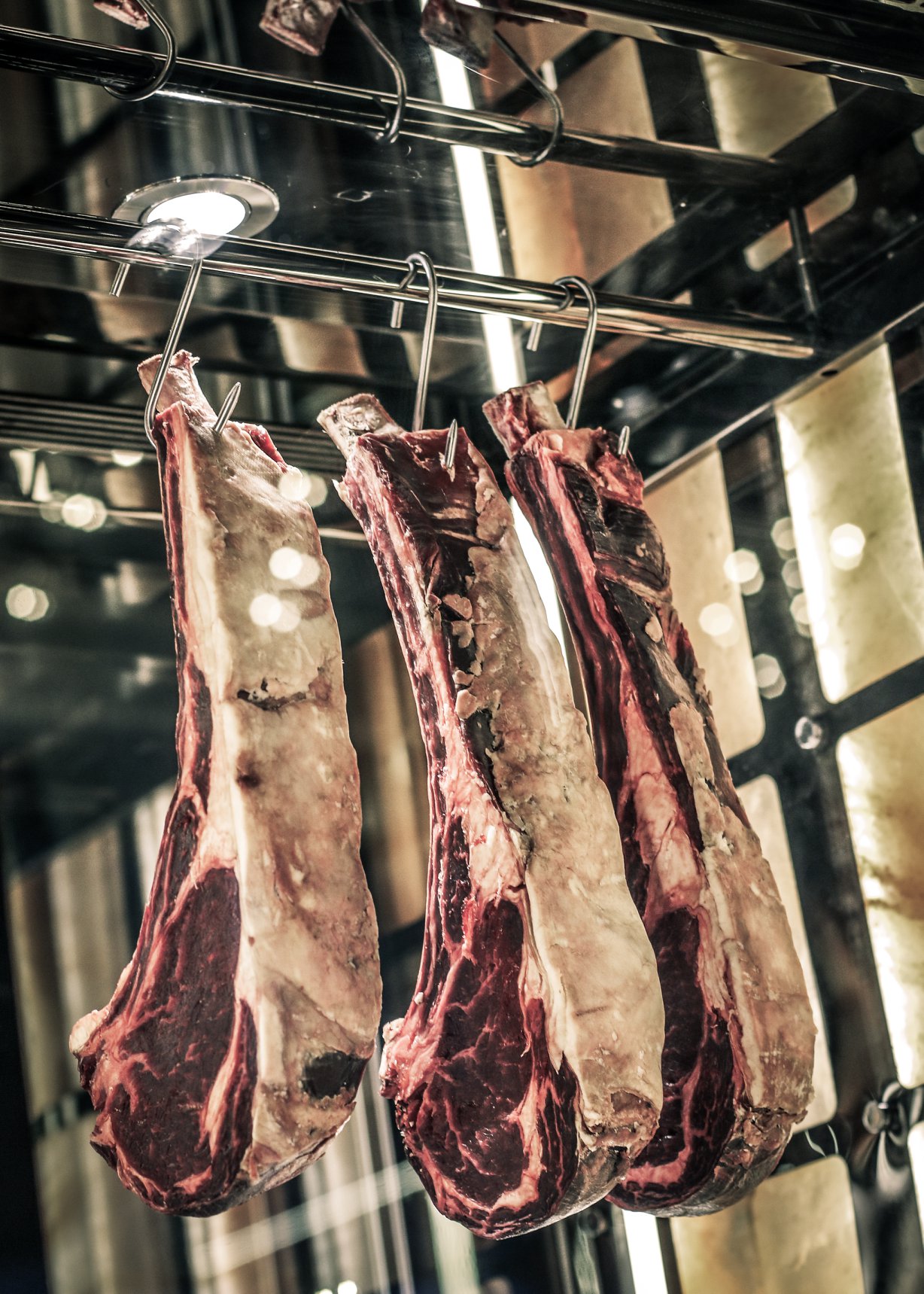 Dry-aged beef cuts hanging in a temperature-controlled meat display at Stellar Steakhouse, showcasing the restaurant’s in-house ageing process and craft-led approach.