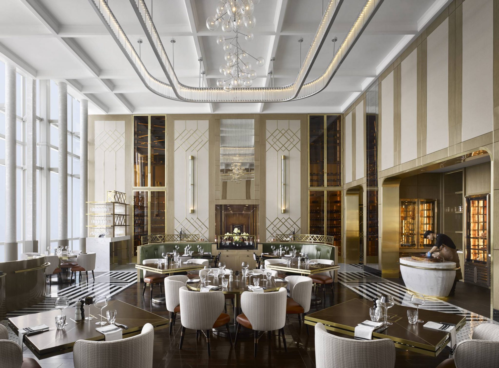 Main dining room of Stellar Steakhouse at InterContinental Hanoi, featuring double-height ceilings, brass detailing, marble accents, patterned flooring, and a central open carving station.