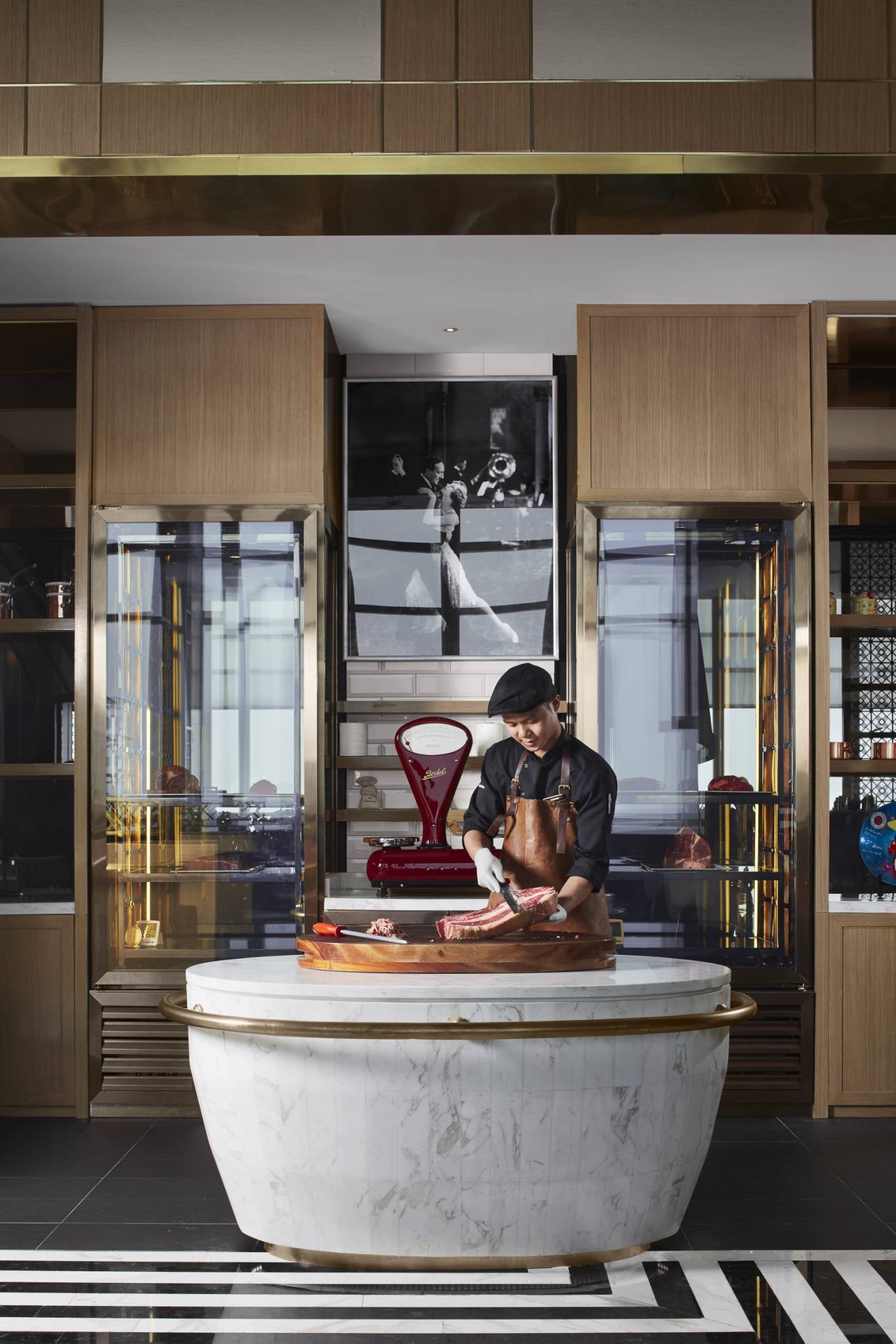 Open carving station at Stellar Steakhouse, InterContinental Hanoi, with a chef preparing prime cuts on a marble counter framed by timber cabinetry and brass detailing.