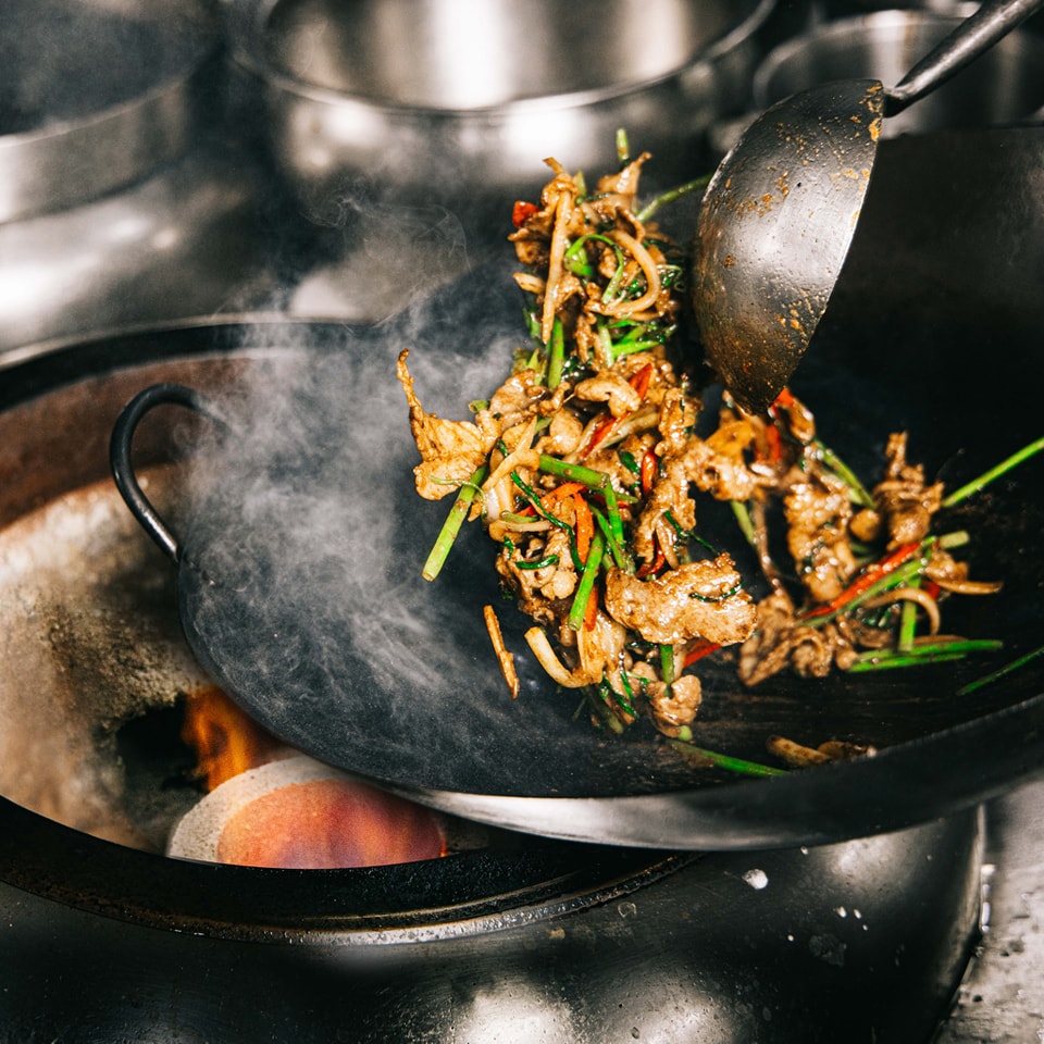 Chef preparing food in a live show kitchen at Grand Café, Grand Hyatt Jakarta, highlighting theatrical all-day dining and a la minute cooking.