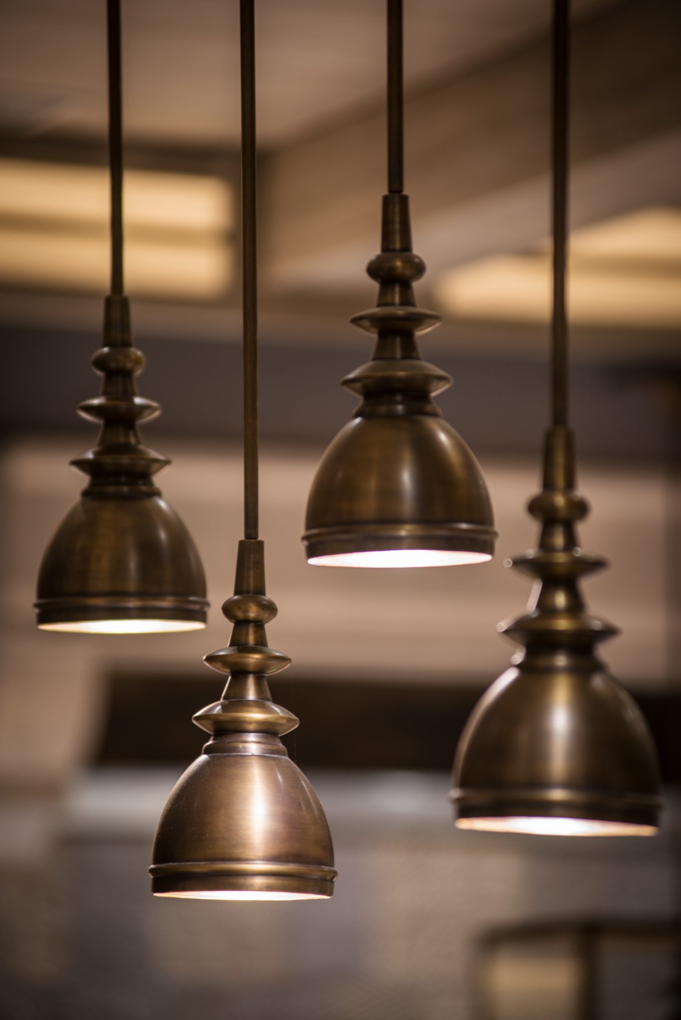 Close-up of brass pendant lighting at Grand Café, Grand Hyatt Jakarta, highlighting warm metallic finishes and layered illumination that enhance the dining atmosphere.