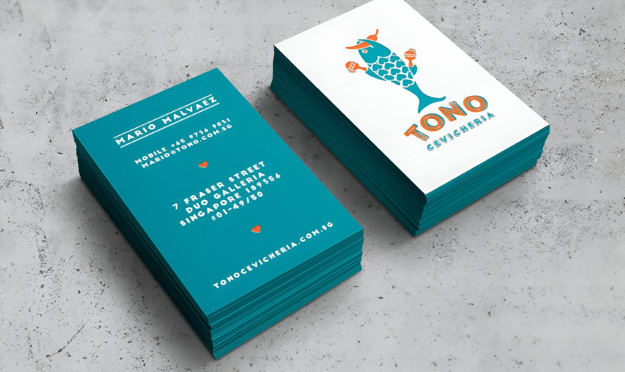Stacked Tono Cevicheria business cards showcasing vibrant teal and white branding, featuring a playful fish logo, bold typography, and contact details, developed as part of the restaurant’s brand identity and collateral design for its Singapore location.